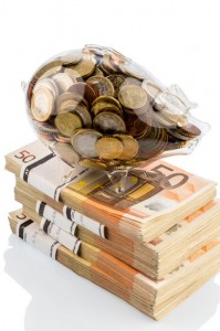 Festgeld Vergleich: Sparschwein voller Münzen steht auf einem Bündel Fünfzig Euro Scheine